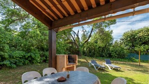 A covered outdoor patio with a table and chairs, surrounded by lush greenery and a barbecue grill. - Cosy apartment in villa for 6 guests with TV, terrace and pets allowed (Coggia)
