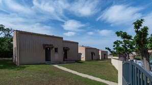 A row of single-story buildings with a flat roof and a small front porch. - Cosy apartment in villa for 6 guests with TV, terrace and pets allowed (Coggia)