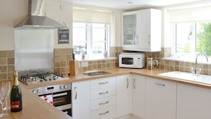 Une cuisine moderne avec des meubles blancs, une cuisinière à gaz, un four à micro-ondes et un évier.