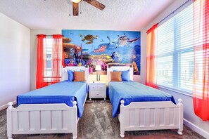 A room with two beds, a ceiling fan, a mural of an underwater scene, and red curtains. - Champion Gate Brand New Home with Private pool and  game room (Davenport)