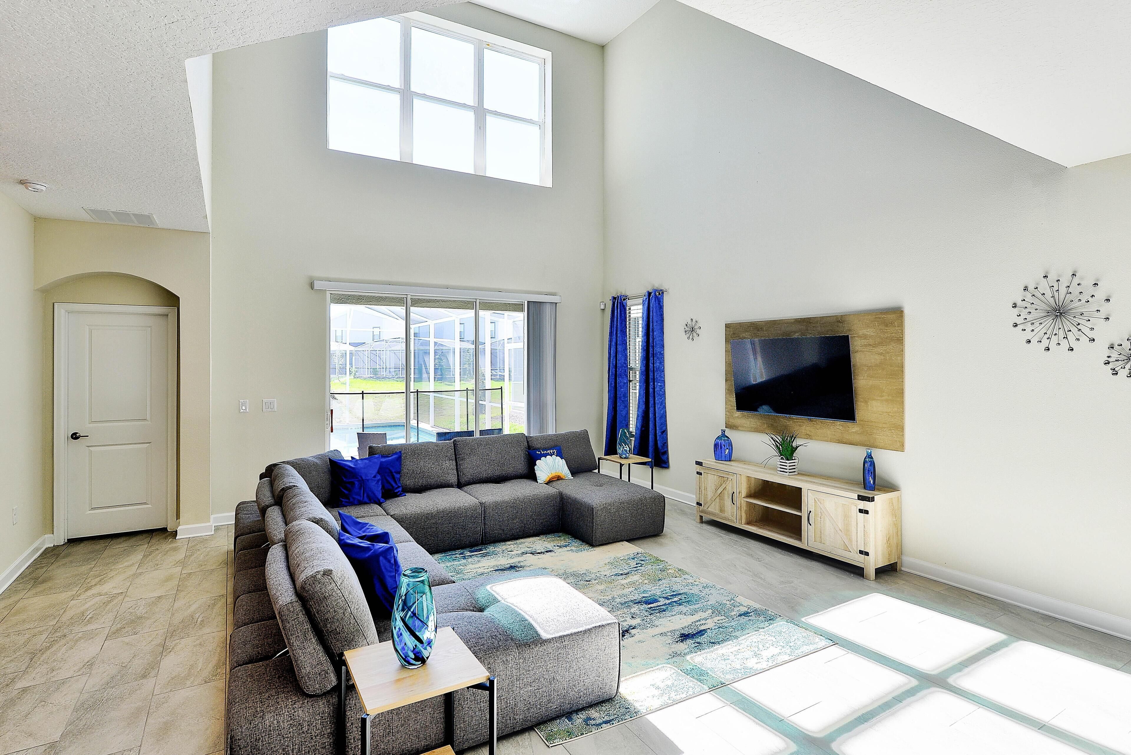 A modern living room with a sectional sofa, a flat-screen TV, and a wooden cabinet.