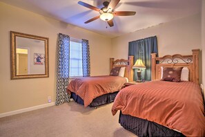 Une chambre avec deux lits, un ventilateur de plafond, une lampe et un miroir.