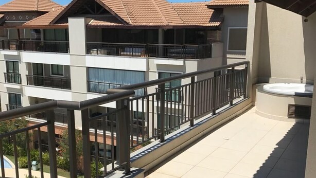 A residential building with multiple balconies, a swimming pool, and a covered outdoor area with a hot tub.