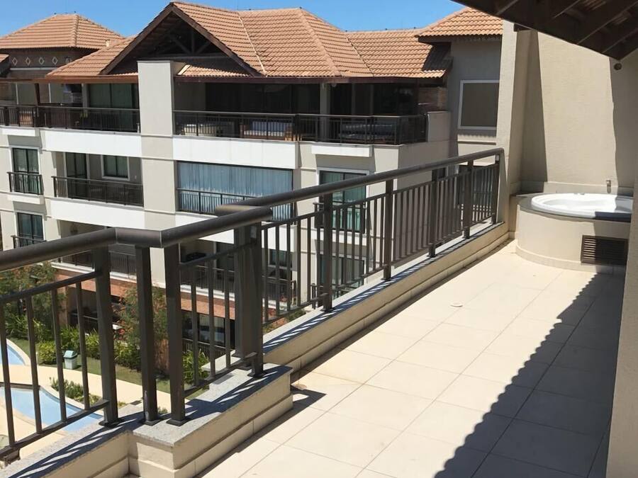 A residential building with multiple balconies, a swimming pool, and a covered outdoor area with a hot tub.
