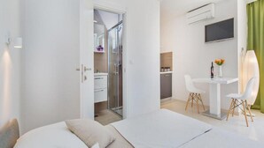 Ein modernes Hotelzimmer mit Bett, Schreibtisch und Duschbereich.
