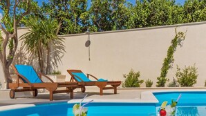 Ein Poolbereich mit Liegestühlen und einem Tisch mit Obst und Getränken.
