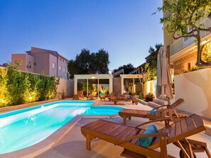 A swimming pool with lounge chairs and a covered seating area.
