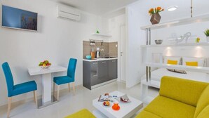 A modern apartment with a dining area, kitchen, and living room. - Apartments St.Thomas - Deluxe Studio with Terrace (Dubrovnik)