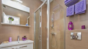 Ein modernes Badezimmer mit einer einteiligen Duschkabine, einem weißen Waschbecken mit Spiegel darüber und einer Toilette.