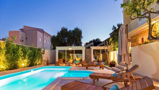 Une piscine avec des chaises longues et un espace salon abrité.