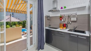 Une cuisine moderne dotée d’un four encastré, d’un évier et d’un plan de travail sur lequel se trouve un panier de fruits.