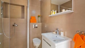 Une salle de bain moderne avec une douche à parois de verre, un lavabo blanc et des toilettes.