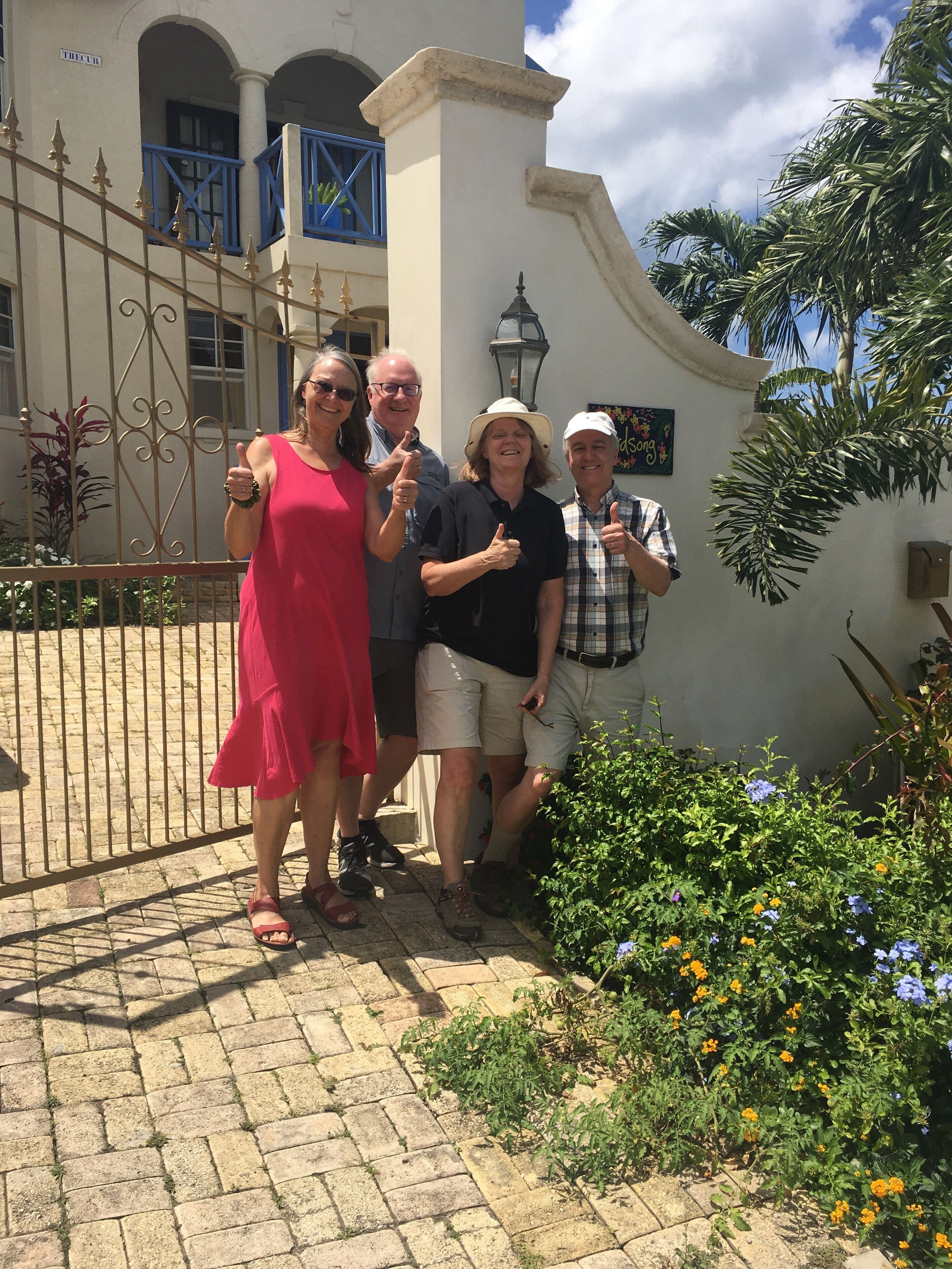 Un groupe de personnes se tient devant un bâtiment orné d’un portail en fer forgé et d’une enseigne sur laquelle on peut lire « THECUR ».