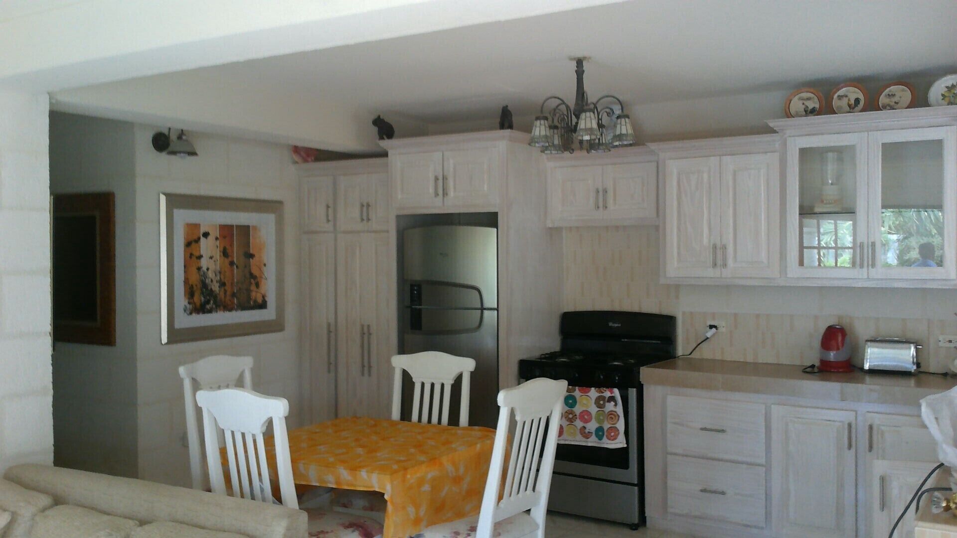 A kitchen with white cabinets, a refrigerator, a stove, and a dining table with chairs.