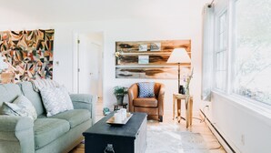 Ein Wohnzimmer mit einem grünen Sofa, einem schwarzen Couchtisch und Holzdielen.