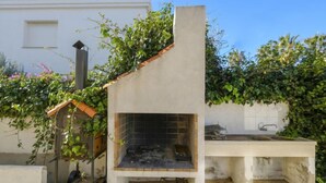 Une cuisine extérieure dotée d’un mur recouvert de carreaux, d’une cheminée et d’un banc.