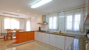 Une cuisine moderne avec un îlot central, des meubles blancs et une grande fenêtre agrémentée de rideaux.
