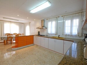 A modern kitchen with a central island, white cabinets, and a large window with curtains.