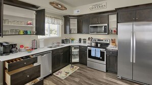 Une cuisine moderne avec des meubles de couleur sombre, des appareils en acier inoxydable et une décoration de style champêtre.