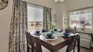 Un coin repas avec une table en bois, dressée pour quatre personnes, entourée de chaises.