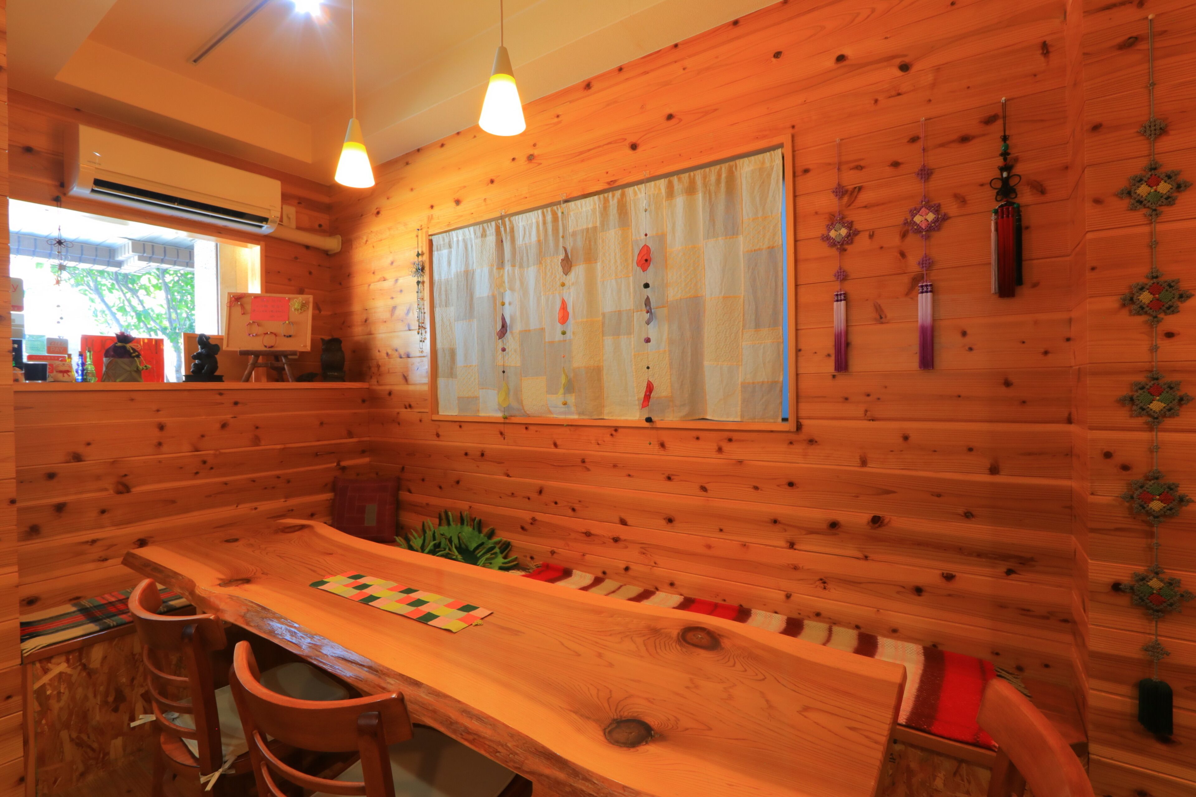 A wooden interior with a long table, chairs, and a hanging decorative piece.