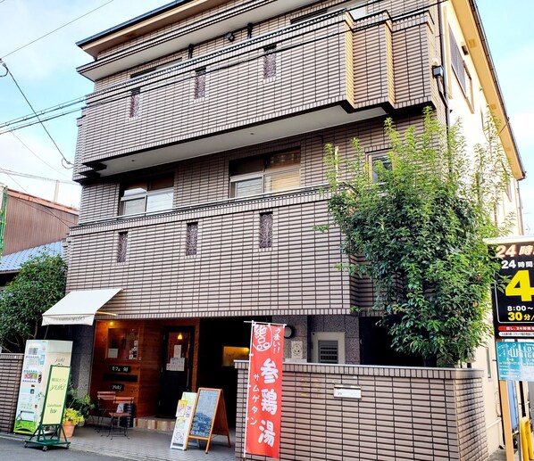 A two-story building with a brick facade, a signboard, and a small awning. - Guesthouse Ivy (Higashi-osaka)