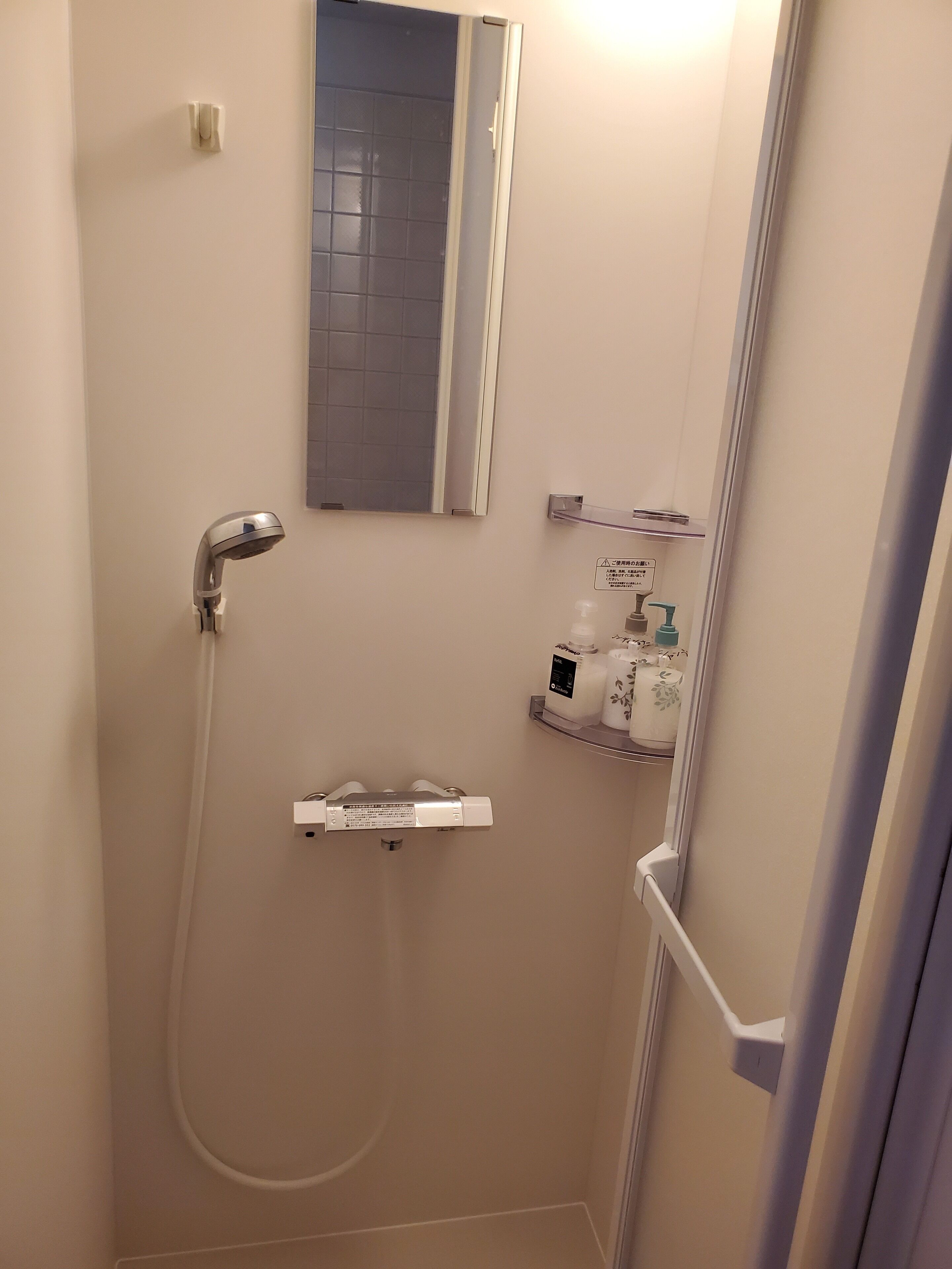 A small, modern bathroom with a shower, a toilet, and a sink.
