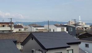 A residential area with various buildings, including houses with different roof styles and a prominent utility pole. - Guesthouse Ivy (Higashi-osaka)