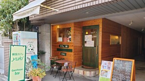 Un café acogedor con paredes de madera, una puerta verde y mesas al aire libre.
