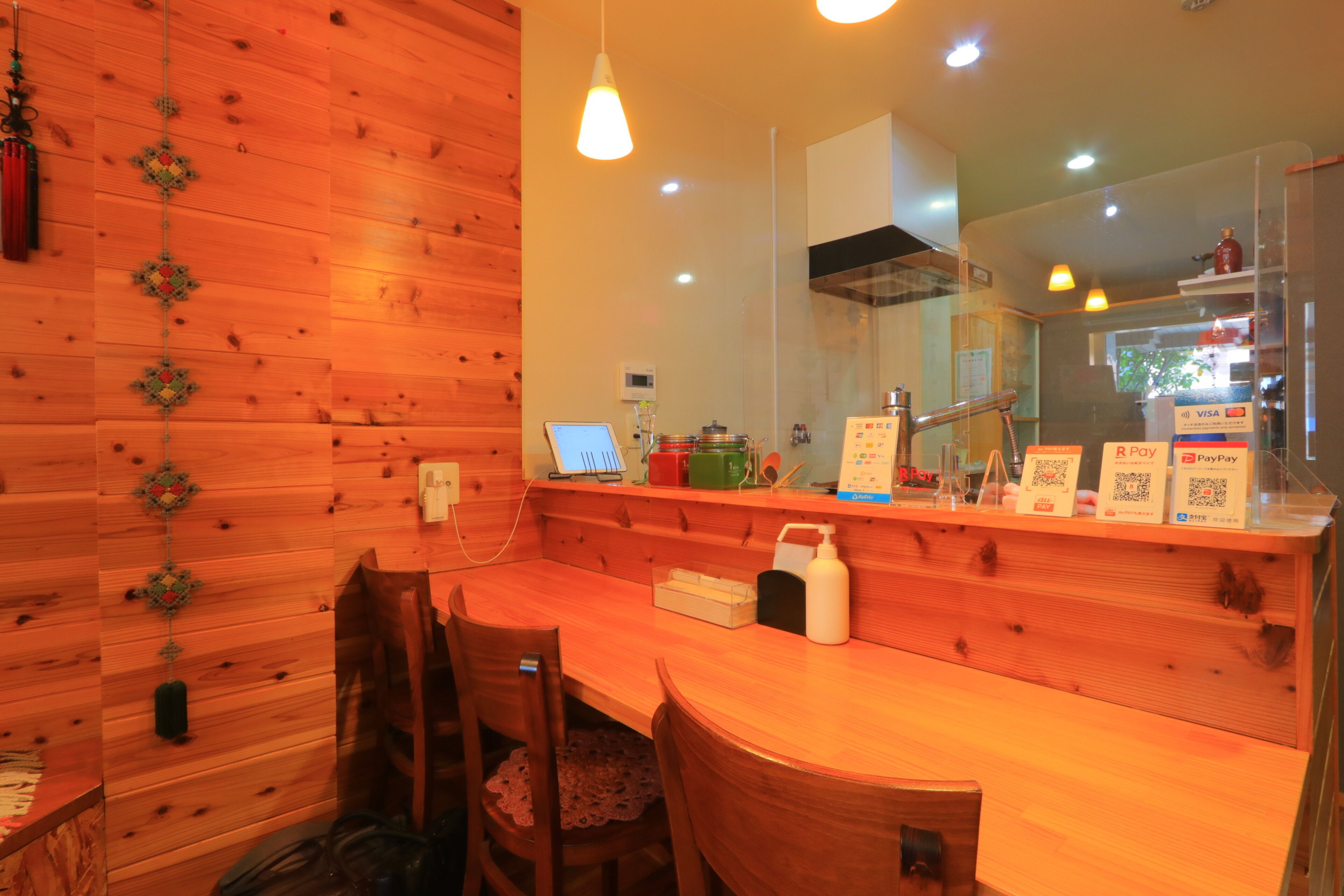 A wooden interior with a wooden table and chairs, a small kitchen area, and a counter with payment options.