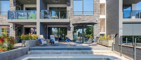A multi-story residential building with a swimming pool, outdoor seating, and balconies.