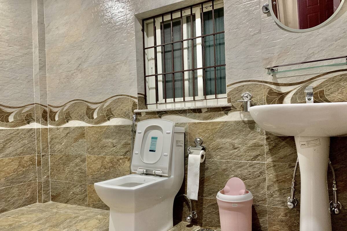 Un baño con inodoro, lavamanos y cubo de basura.
