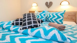 A bed with a blue and white patterned bedspread, two black and white pillows, and a folded towel. - Apartment Laura by Interhome (Zell am Ziller)