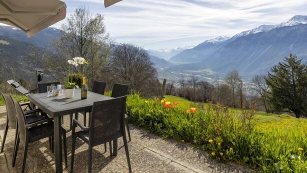 An outdoor dining area with a table and chairs, overlooking a mountainous landscape. - Maison Le Fontany by Interhome (Crans-Montana)