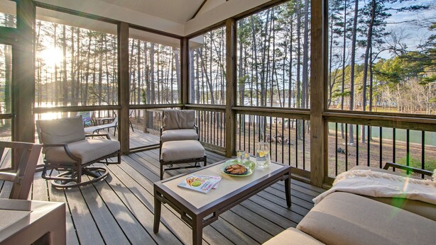 A wooden deck with a sofa, chairs, and a table with a plate and glasses.