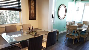 A modern dining area with a glass table, metal chairs, and a decorative wall piece.