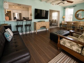 A living room with a dark leather sofa, a wooden coffee table, and a television mounted on the wall.