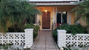A house with a tiled entrance, a wooden door, and a small porch area.