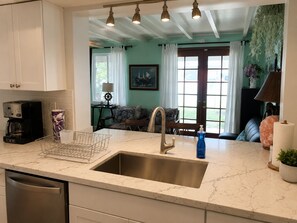 A kitchen with a stainless steel sink, a coffee maker, and a basket on the counter.