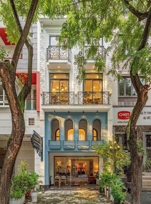 En bygning med flere etager, der har en restaurant i stueetagen, en balkon på anden sal med detaljerede gelændere og en balkon på tredje sal med udsigt.