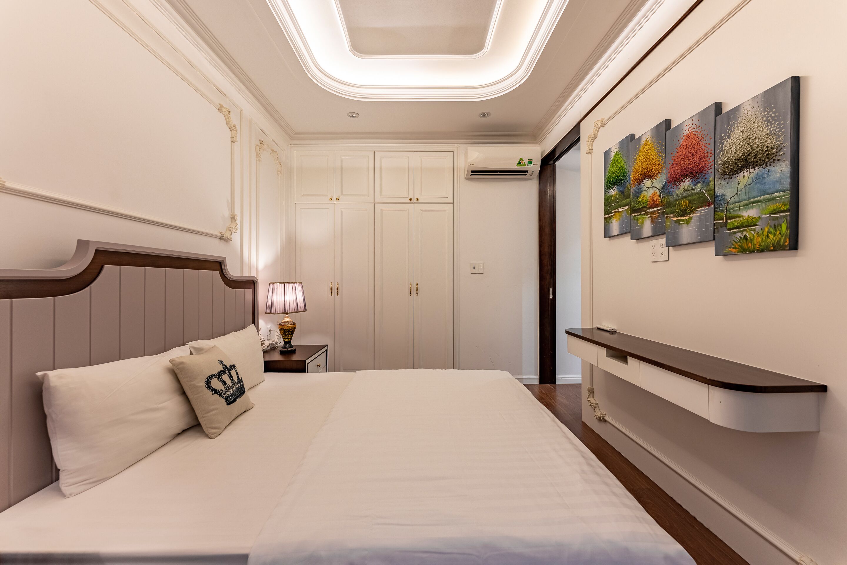 Un dormitorio moderno con una cama grande, una mesita de noche, un estante en la pared y una lámpara del techo.