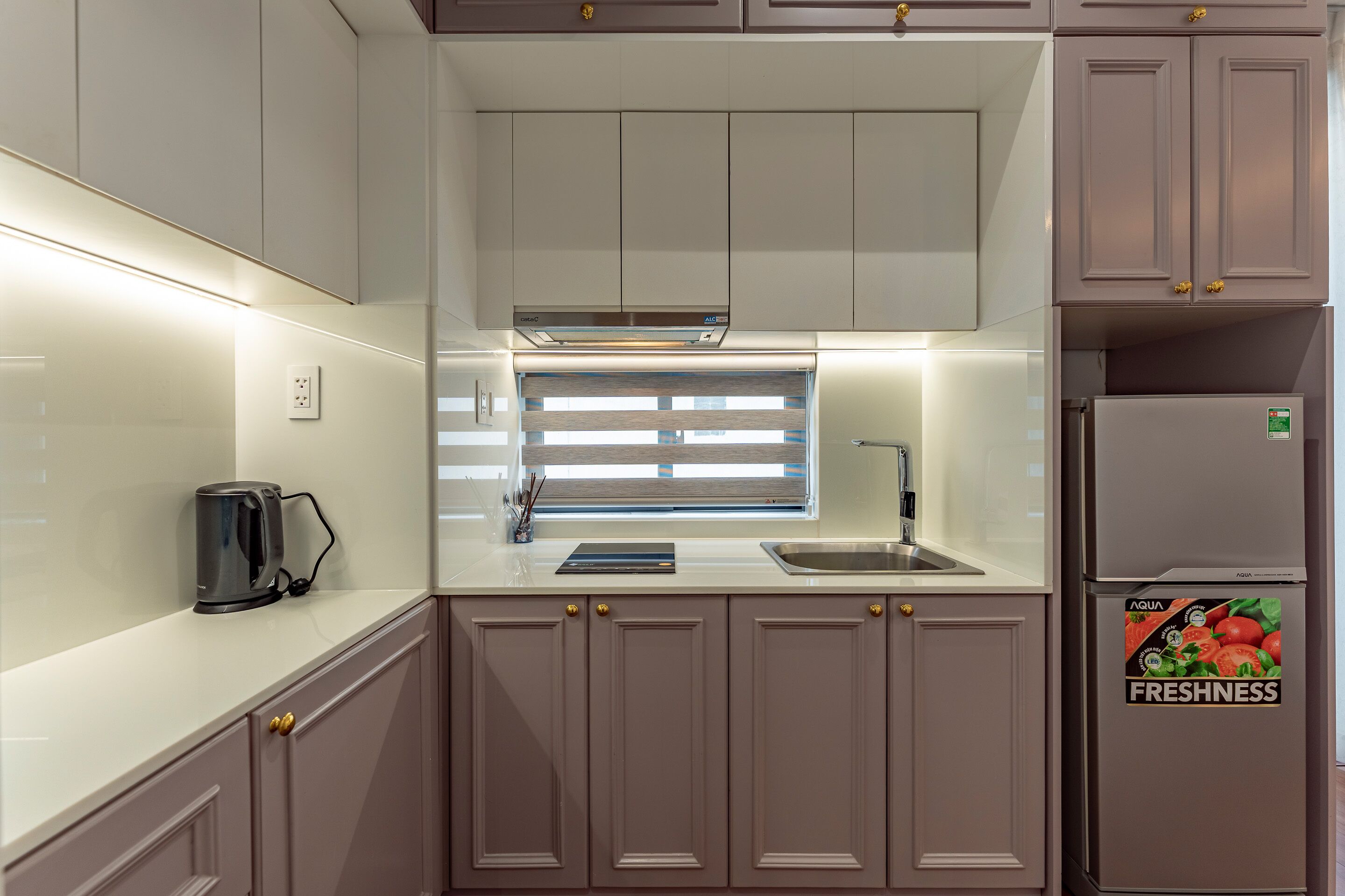 A compact kitchen with a built-in oven, a coffee maker, and a refrigerator with a freshness sticker.