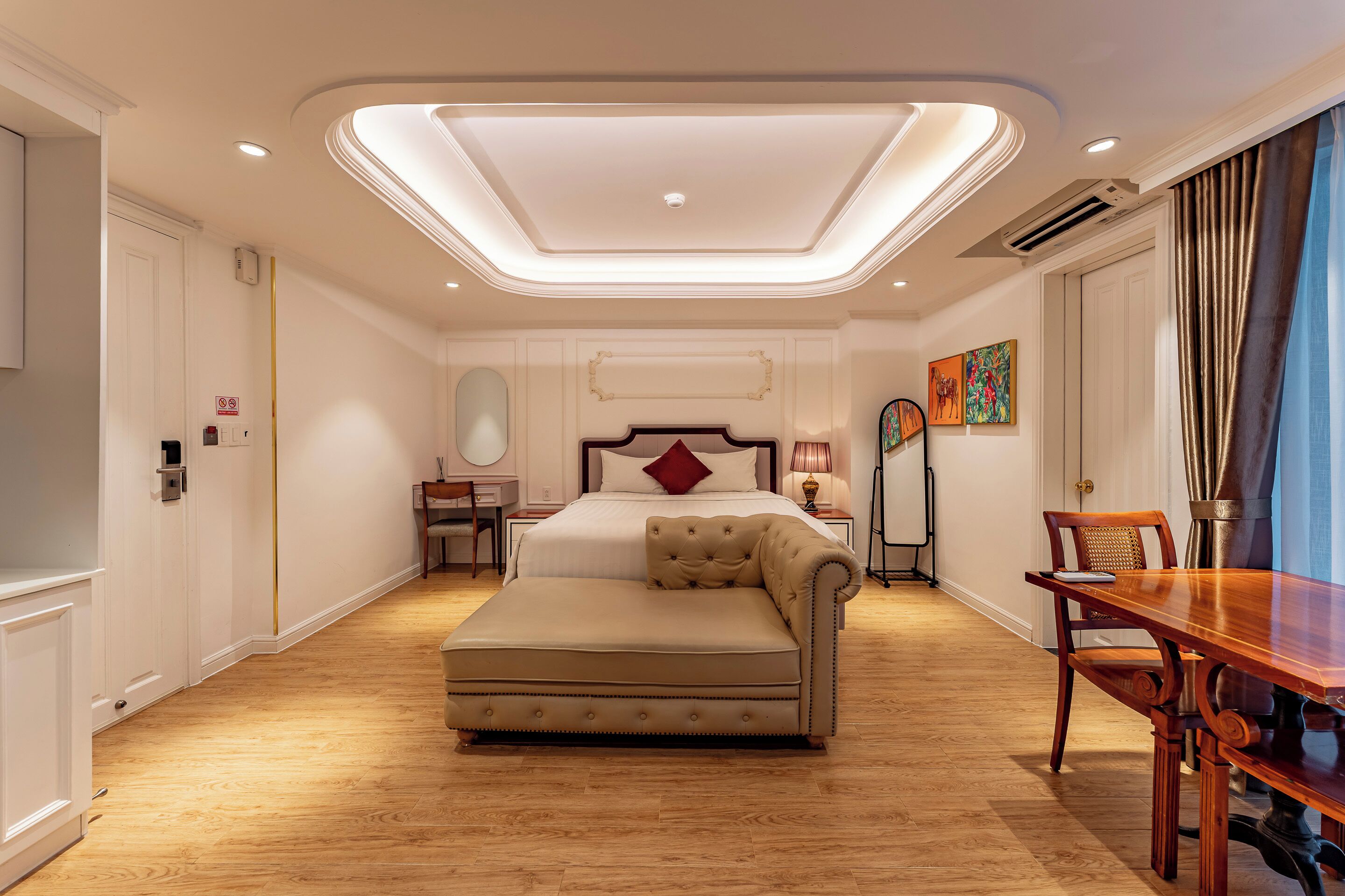 Une chambre d’hôtel moderne avec un grand lit, un canapé, une table à manger et un lustre.