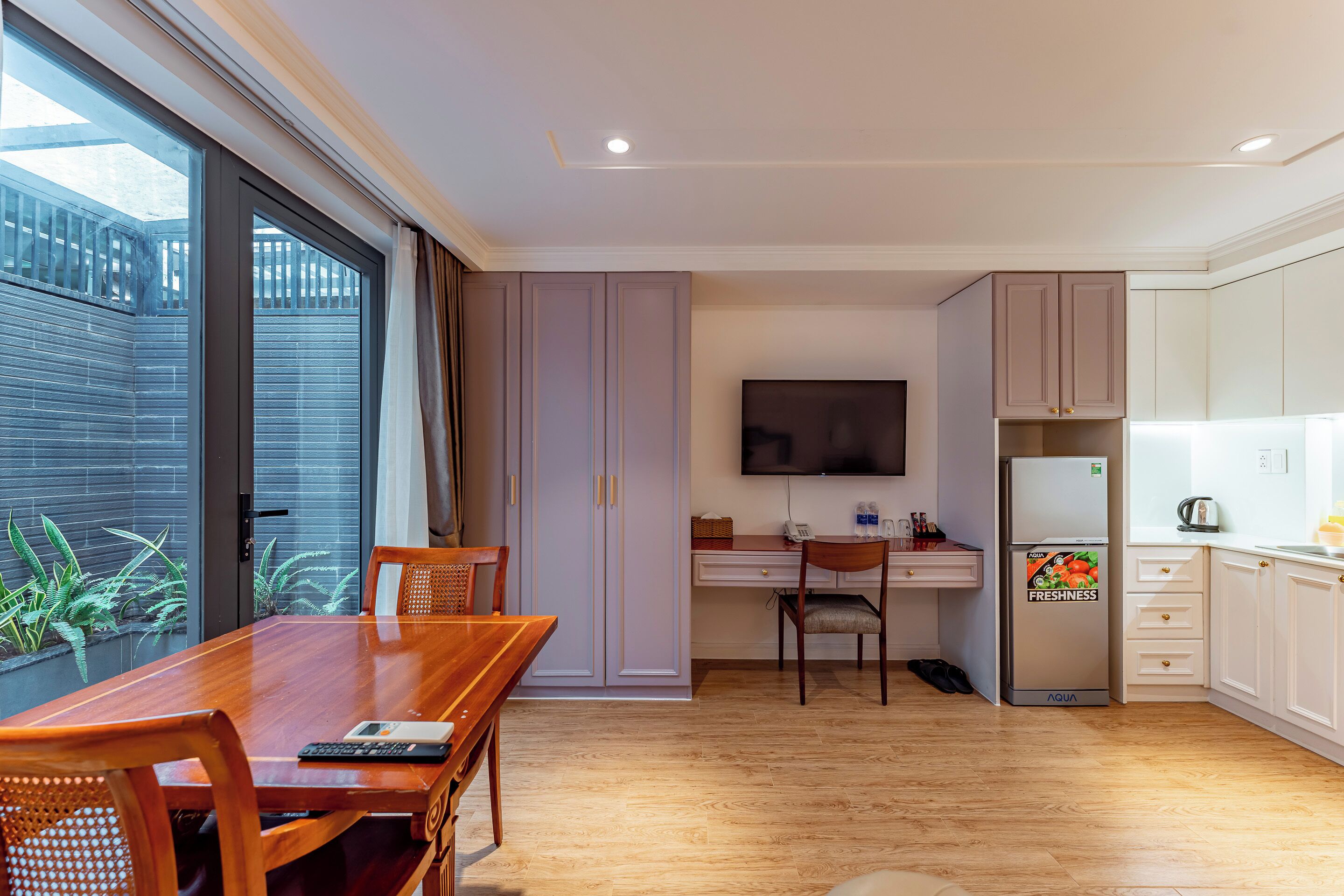 Una cocina moderna con comedor, televisor de pantalla plana y refrigerador.
