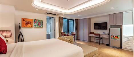 A hotel room with a large bed, a desk, a television, and a minibar.
