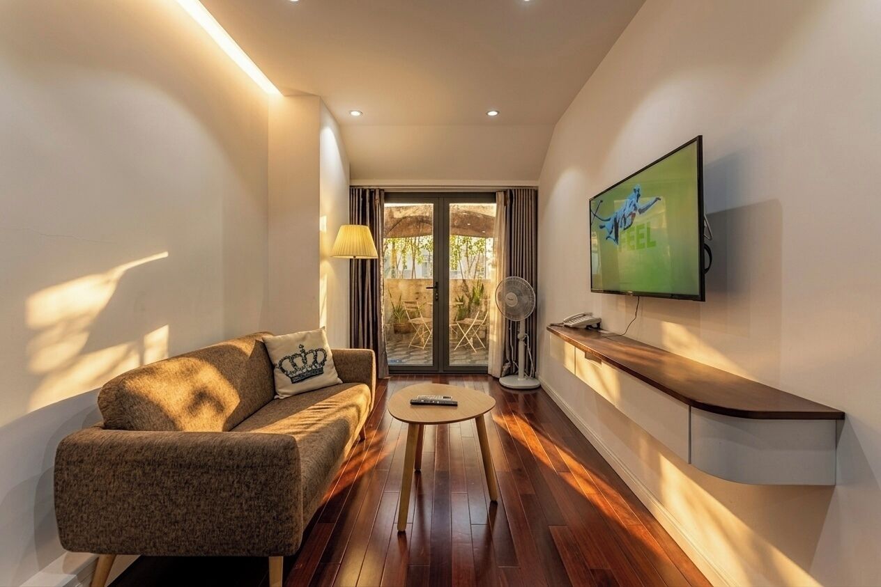 Una sala de estar moderna con un sofá, una mesa de centro, un televisor montado en la pared y un ventanal corredero que da a un espacio exterior.