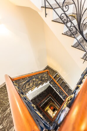 A spiral staircase with ornate metal railings and a polished wooden handrail. - Ngan Ha Apartment 2 (Ho Chi Minh City)
