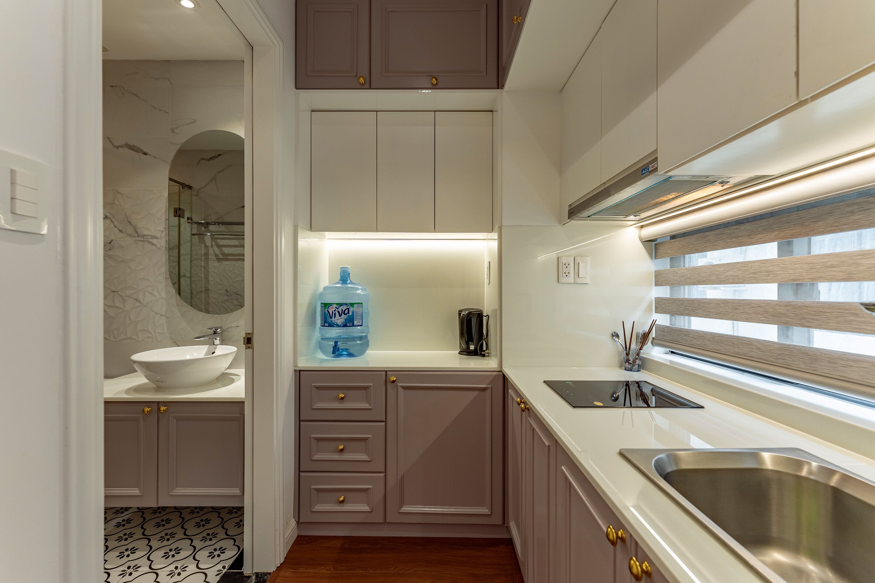 A modern kitchen with a large water dispenser, a sink, and a window with blinds.