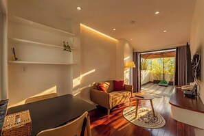 A modern living room with a sofa, coffee table, and a dining area with a table and chairs.