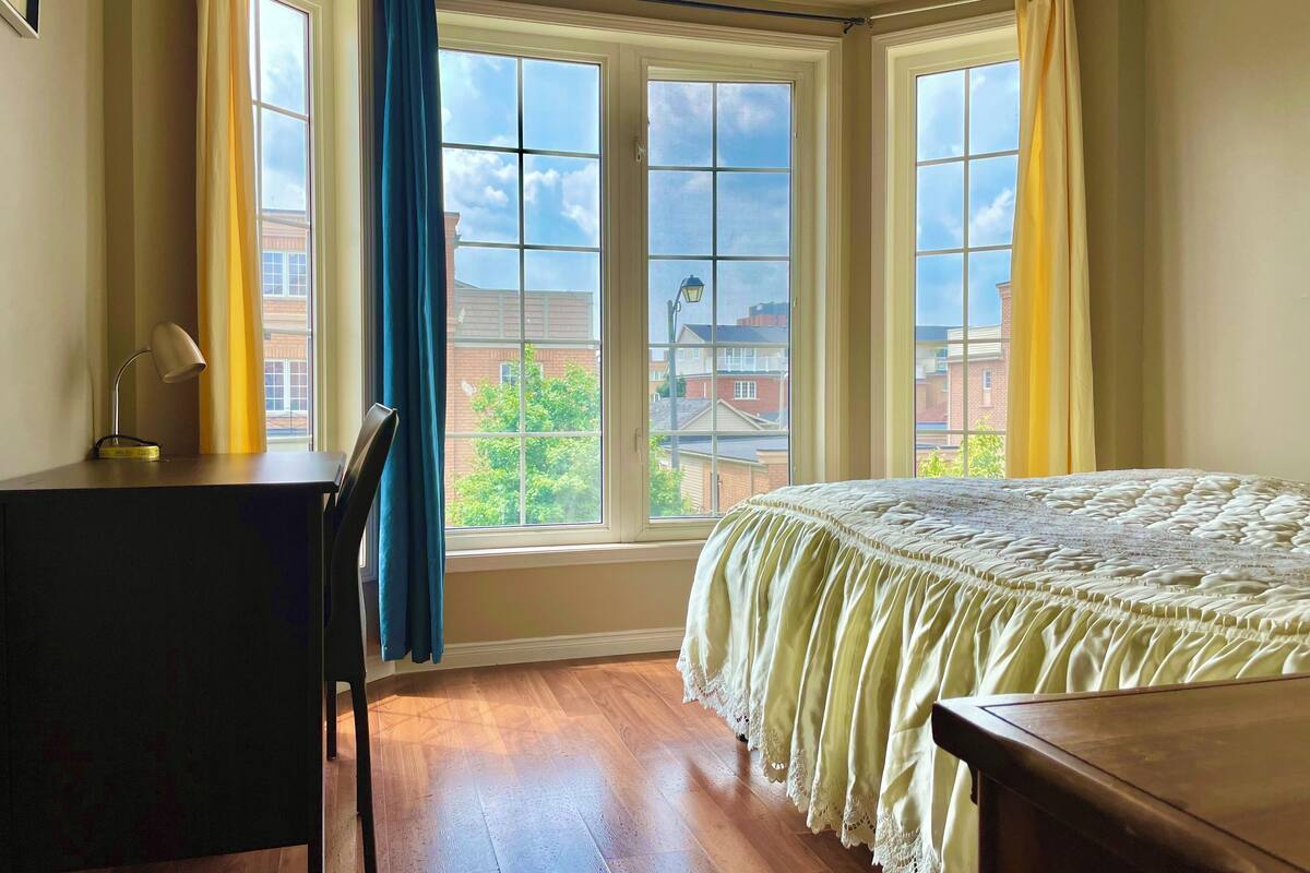 Un dormitorio con cama, escritorio y ventana con cortinas.